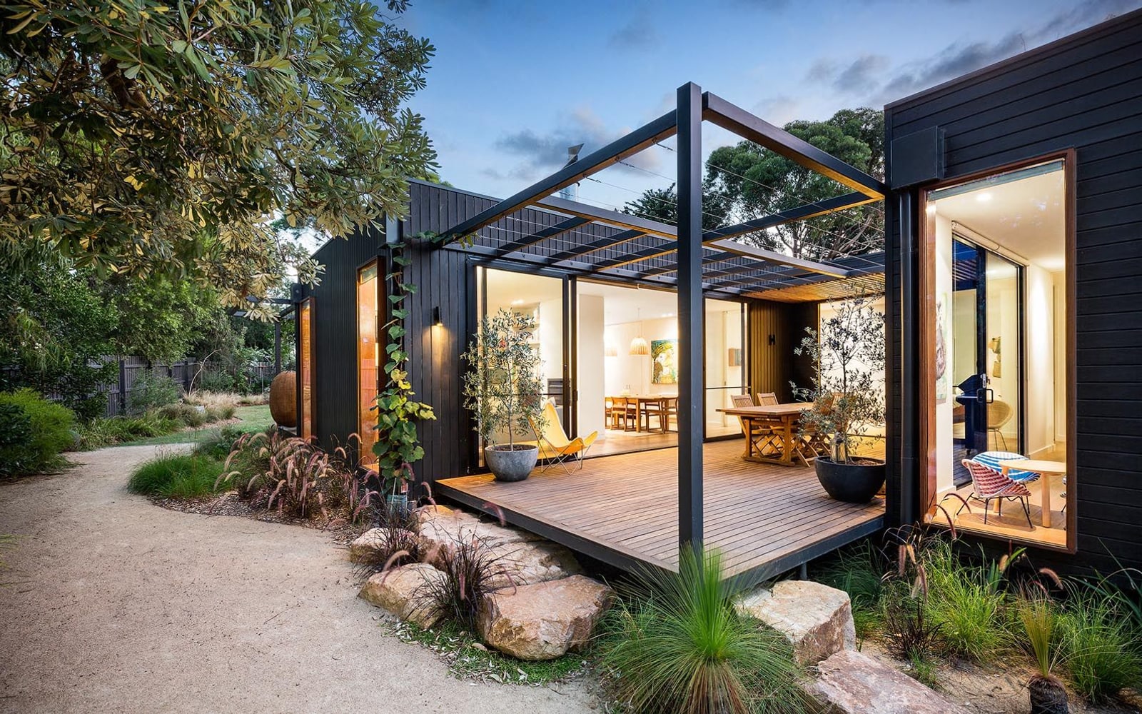 Illustrative reference of a black-framed residence opening onto a gravel court